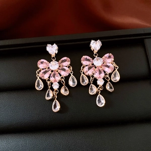 Detail of water drop tassel earrings with pink and white zircon on a black tray