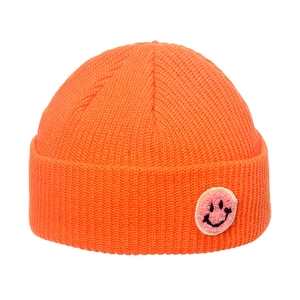 Detailed knit texture of orange ribbed beanie with pink smiley face patch detail