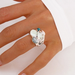 Close-up of wide textured silver ring with white shell pieces and colorful gemstones