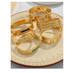 Detailed view of five gold-plated bangles with vintage floral patterns and gemstone accents