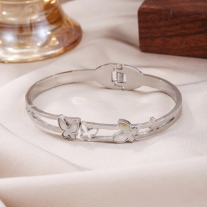 Detailed close-up of a silver stainless steel butterfly bangle with white shell inlay