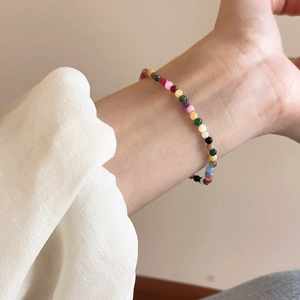 Makroaufnahme eines bunten Edelstein-Armbands aus Erdbeerkristall am Handgelenk einer Frau