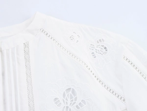 Dettaglio del ricamo floreale traforato bianco e pizzo su colletto e spalla della camicia