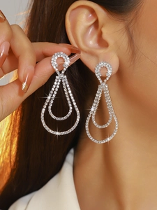 Macro shot of silver rhinestone double drop earrings worn by a model in bright light