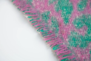 Detailed macro shot of soft pink and green plaid scarf texture with fringed edges