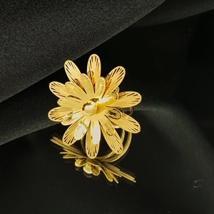 Detailed macro view of gold hollow-out floral ring with layered petals and pearl center