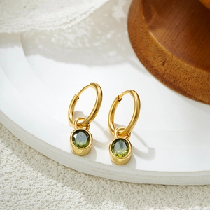 Macro shot of gold stainless steel hoop earrings with detachable green oval gemstones