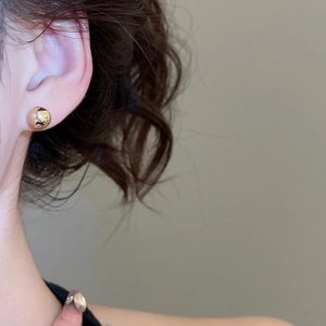 Close-up of minimalist gold bead stud earring worn by model for a stylish look