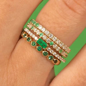 Macro shot of gold-plated S925 silver rings with emerald gems and diamonds in a stack