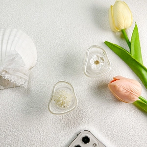 Detailed view of transparent phone grips with embedded pearls and floral resin designs