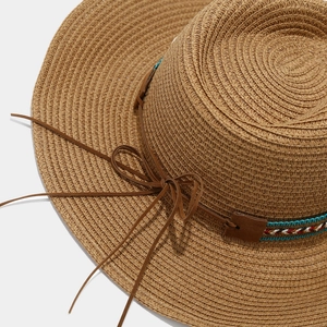 Close-up of bohemian straw sun hat featuring ethnic woven bands and seashell accents