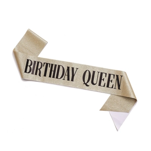 Detail of a sparkling gold glitter Birthday Queen sash for party celebrations