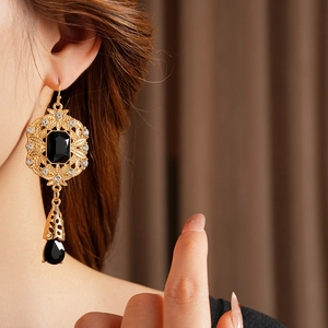Close-up of vintage palace-style gold drop earrings with black gems and crystals