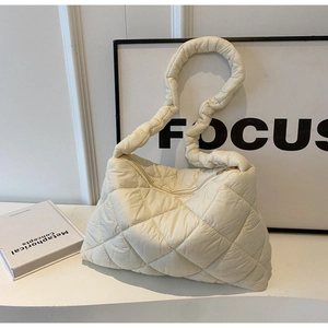 Close-up of cream white quilted shoulder bag featuring elegant ruched handles and zipper
