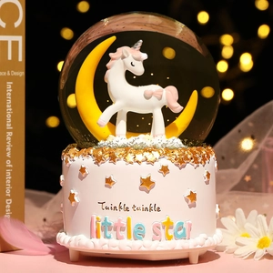 Macro detail of unicorn music box showing a golden crescent moon and glittery star base