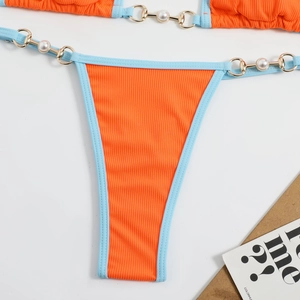 Détail du bas de bikini orange côtelé avec bordure bleue et anneaux en métal doré