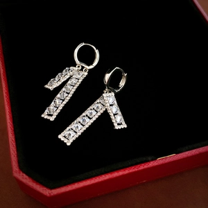 Macro detail of silver geometric drop earrings with sparkling cubic zirconia on black velvet