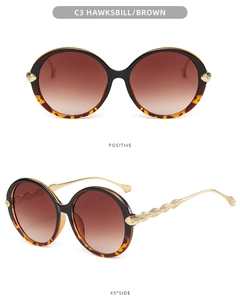 Detail of round tortoiseshell sunglasses with textured gold metal temples and brown lenses