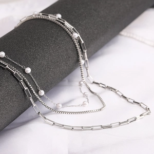 Detail of silver triple-layered necklace featuring paperclip, pearl, and box chain links