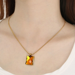 Gold snake chain necklace with a vintage rectangular amber glass stone pendant on a model