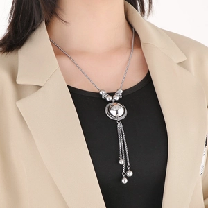Detail view of long silver tassel pendant necklace with metal beads on a fashion model