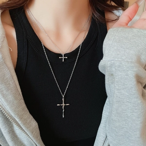 Close-up of double-layer silver cross necklace on neck with irregular metal textures