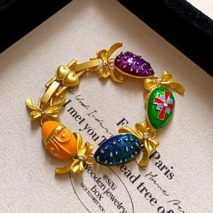 Détail d'un bracelet doré vintage avec breloques émaillées et maillons noeuds