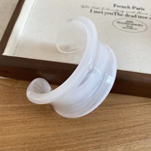 Close-up of translucent white acrylic wide bangle with a minimalist twisted design