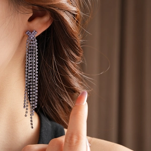 Gros plan de longues boucles d'oreilles à pompons violets avec strass sur un modèle