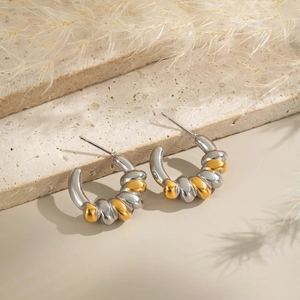 Detailed view of two-tone twisted C-shape hoop earrings on a textured stone