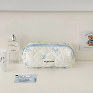 Detailed macro view of quilted makeup bag with blue bow pattern and brand label