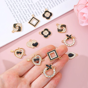 Pendentifs dorés en alliage avec émail noir et strass sur fond rose et livre