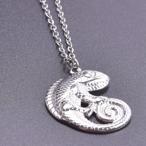 Macro detail of silver lizard pendant with intricate scales on a black textured surface