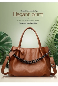 Detail view of caramel leather tote bag with bow decoration and metallic chain accent