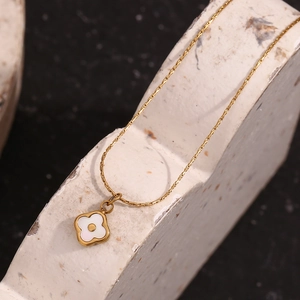 Macro detail of a 18K gold plated necklace featuring a white shell flower pendant