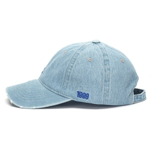 Detail of light blue denim baseball cap featuring vintage 1999 embroidery and frayed edges
