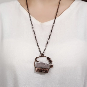 Vintage bronze necklace with moon, stars and light amethyst pendant on white linen shirt