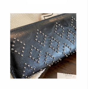 Detail der schwarzen Leder-Clutch mit silbernen geometrischen Nieten und hoher Textur