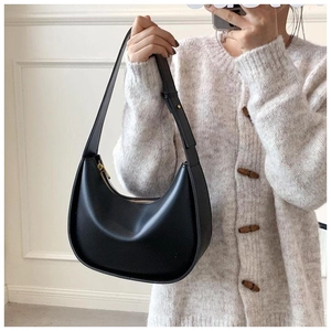 Gros plan d'un sac demi-lune noir avec fermeture éclair dorée et bandoulière réglable