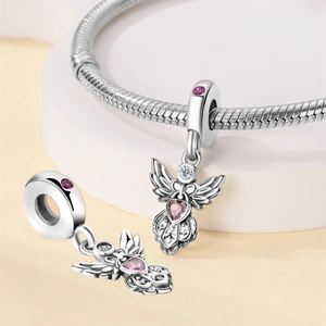Macro view of winged angel charms with pink heart crystals in silver finish