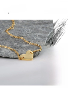 Gros plan d'un pendentif cœur doré avec la lettre D gravée sur une surface métallique polie