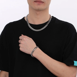 Polished silver cuban link necklace and bracelet set worn by male model on white background
