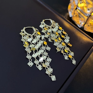 Macro detail of gold and silver leaf tassel earrings with sparkling diamond-shaped sequins