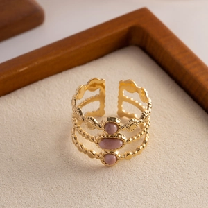 Macro detail of a triple-layered gold ring featuring three pink oval natural stones