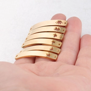 Detail showing curved gold stainless steel connectors with hollow charm patterns in hand
