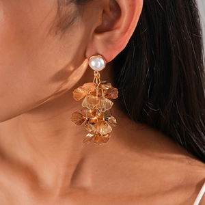Detail of elegant gold ginkgo leaf tassel earrings with white pearl on female model