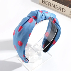 Detailed view of a blue knotted headband with red tennis ball patterns on a display stand