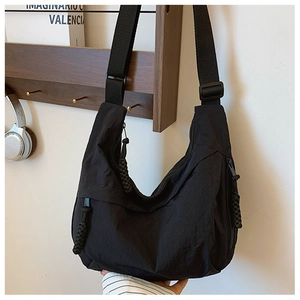 Dettaglio della borsa a tracolla in nylon nero con tasche multiple a zip e ampio scomparto principale
