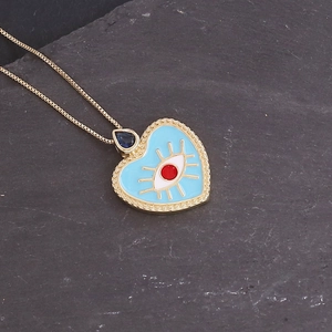 Detail of 18K gold evil eye heart pendant with blue enamel and tiny gemstone