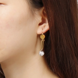 Elegant gold drop earrings with pearl cage pendant on female model side profile